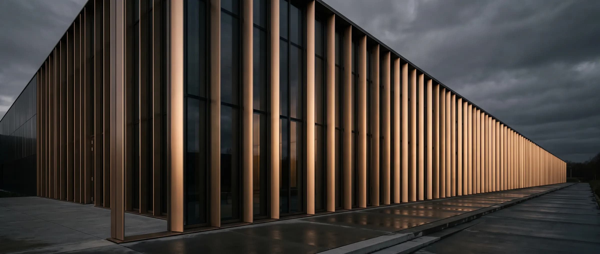Bronze fins along a contemporary building facade receding into dusk